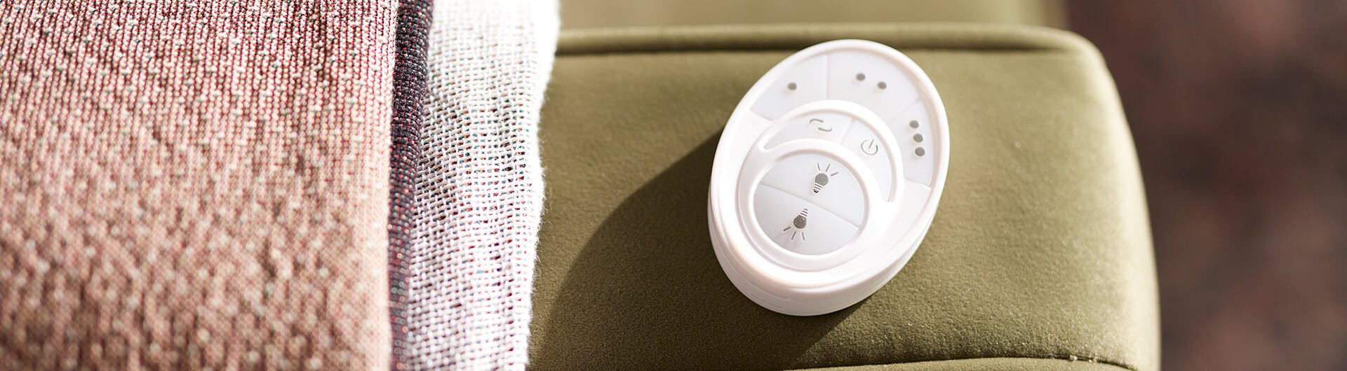 Close-up of a fan remote sitting on a chair arm