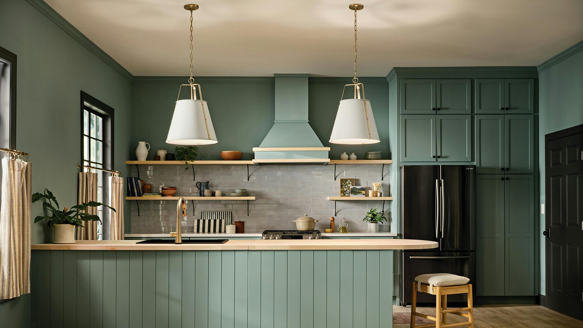 Green kitchen with natural wood countertops and 2 Etcher Pendents hanging above peninsula