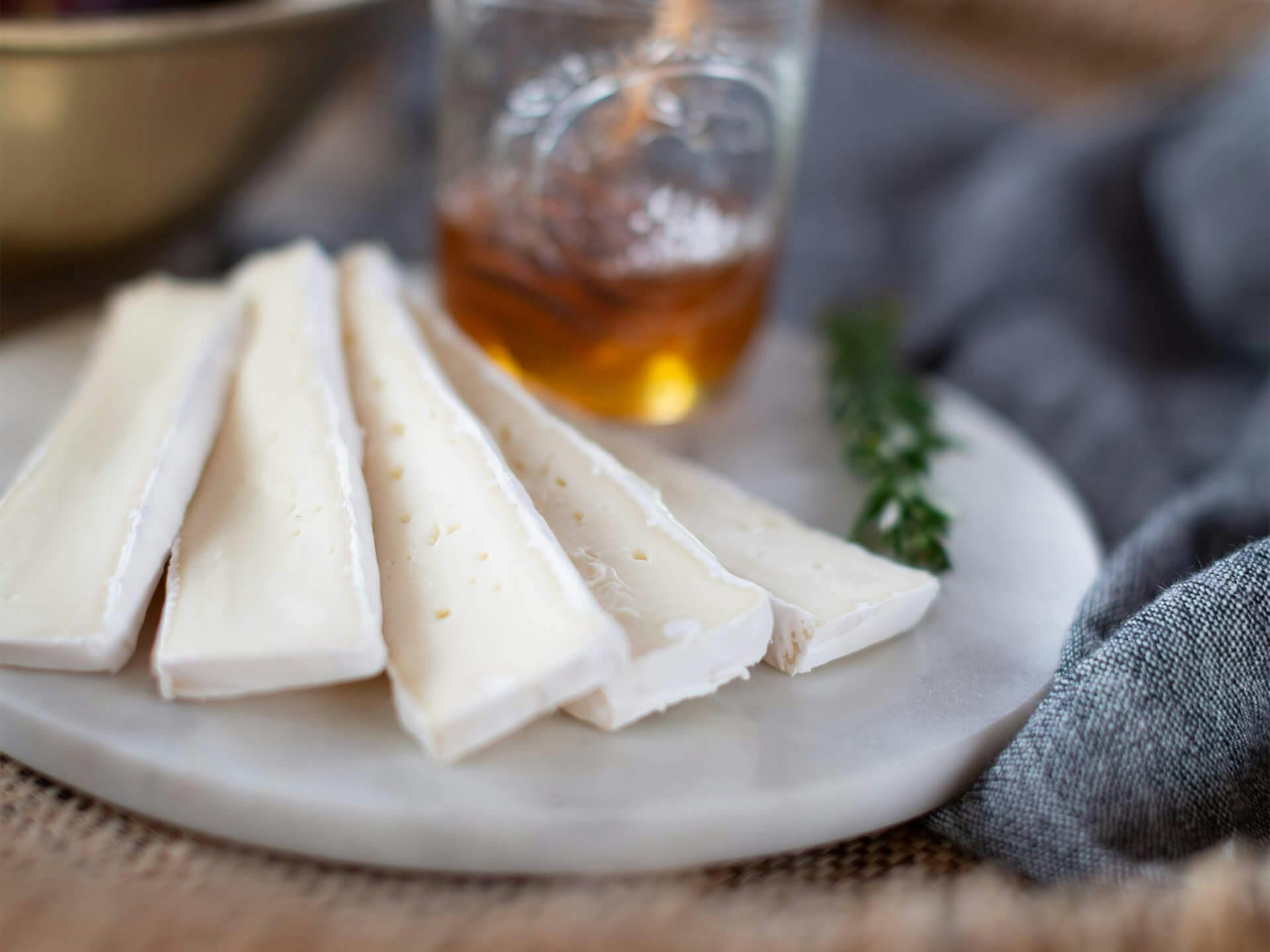 a platter of brie cheese and a jar of honey