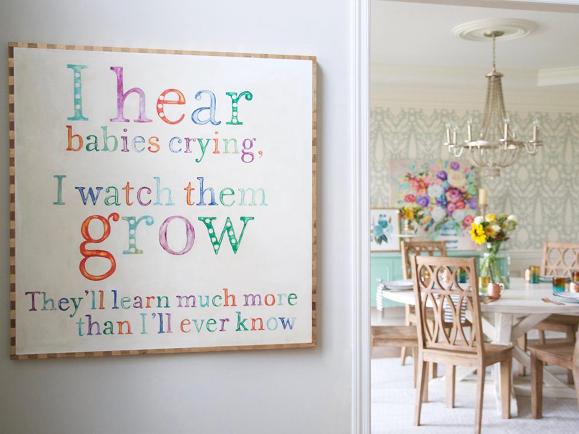 Looking in on The Handmade Home's rustic summer dining room from the hallway. A sign out side the doorway that says I hear babies crying, I watch them grow, they'll learn much more than I'll ever know