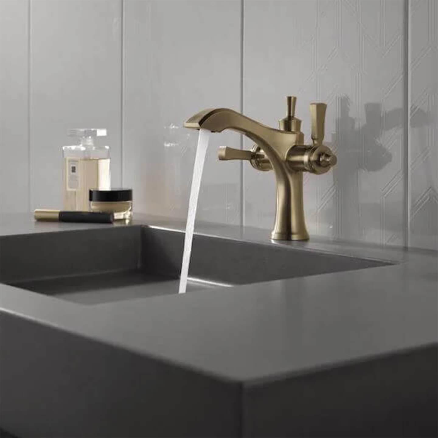 Champagne Bronze faucet with water running into a dark stone sink