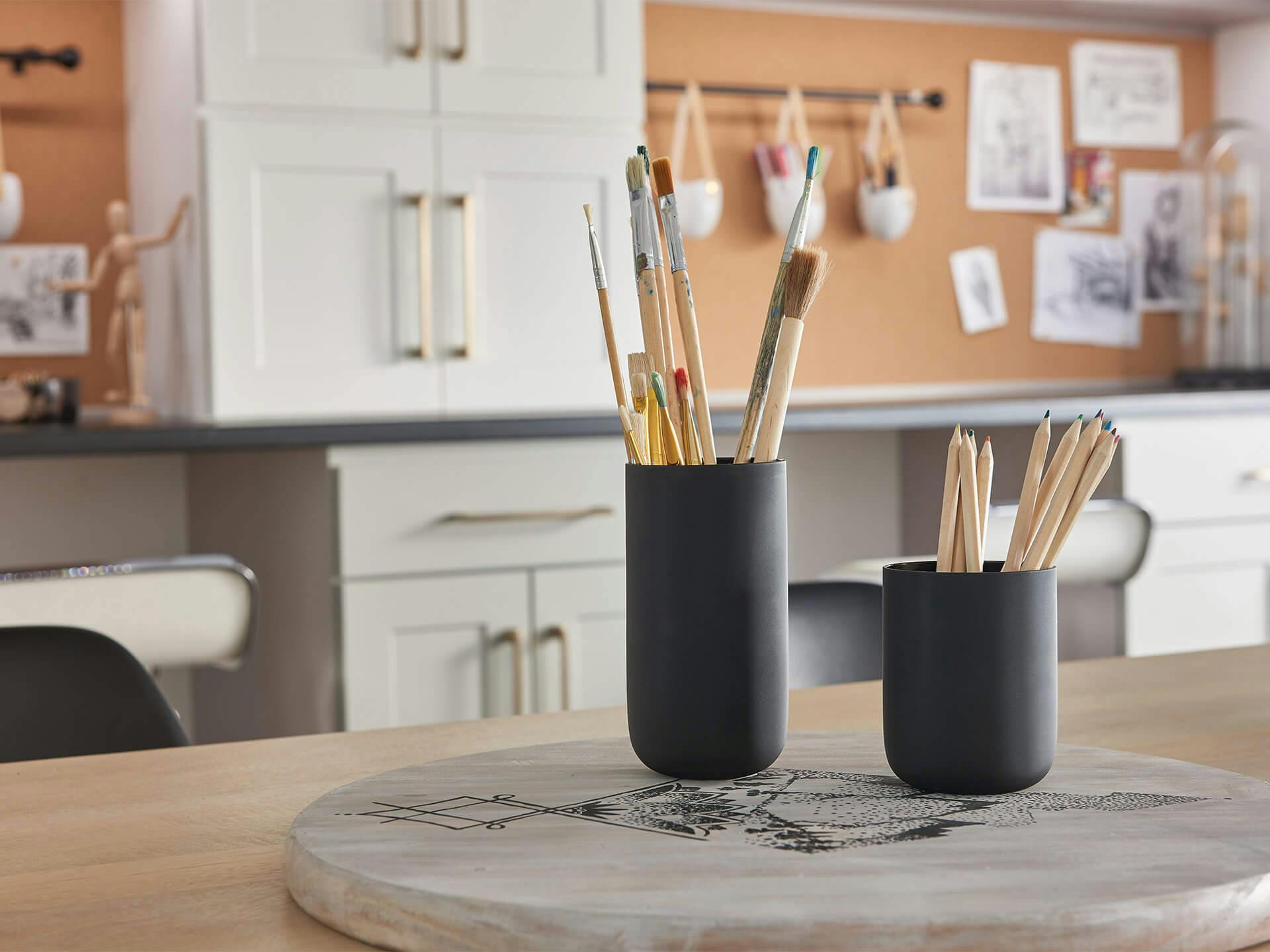 Pencil holders filled with pencils on a desk lit by the Starkk lighting system