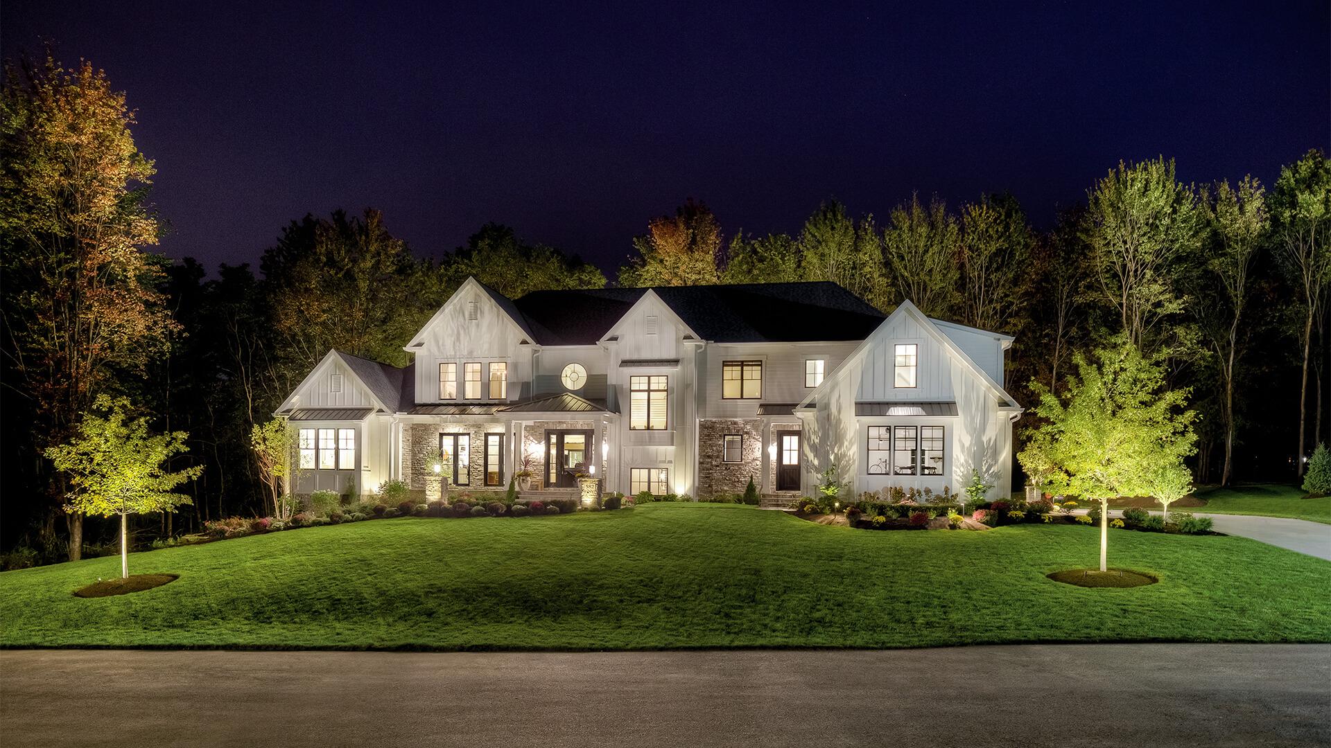 Landscape photo of a home at night lit up by a variety of lights