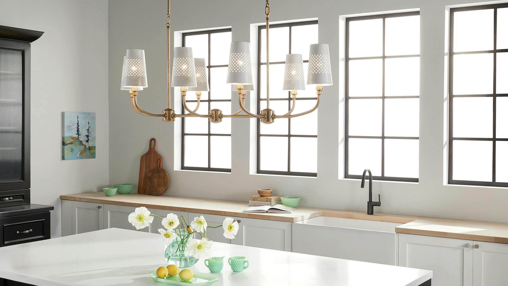 Bright kitchen during the day featuring Adeena chandelier over the white counter.