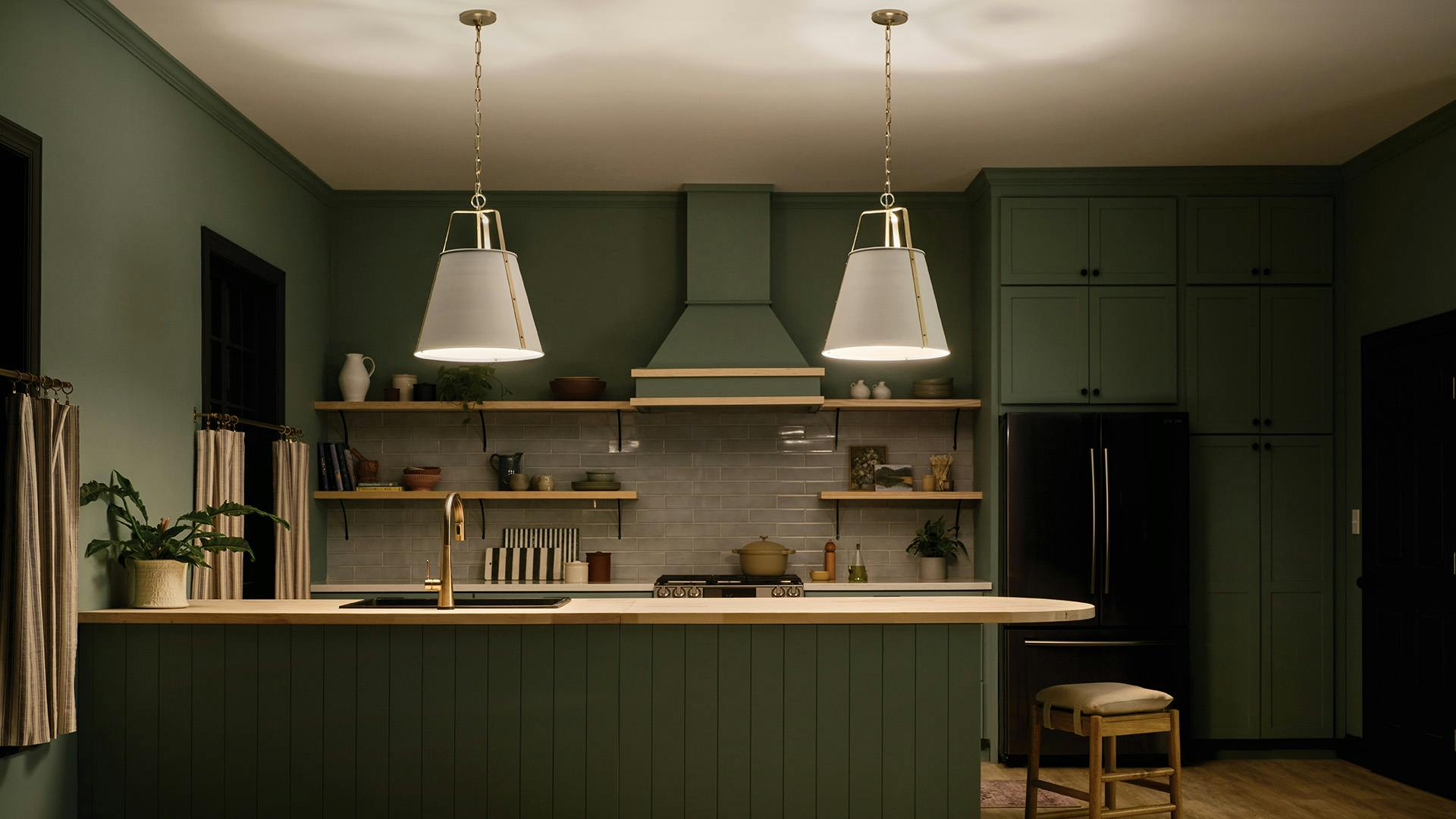 Green kitchen with natural wood countertops and 2 Etcher Pendents hanging above peninsula at night