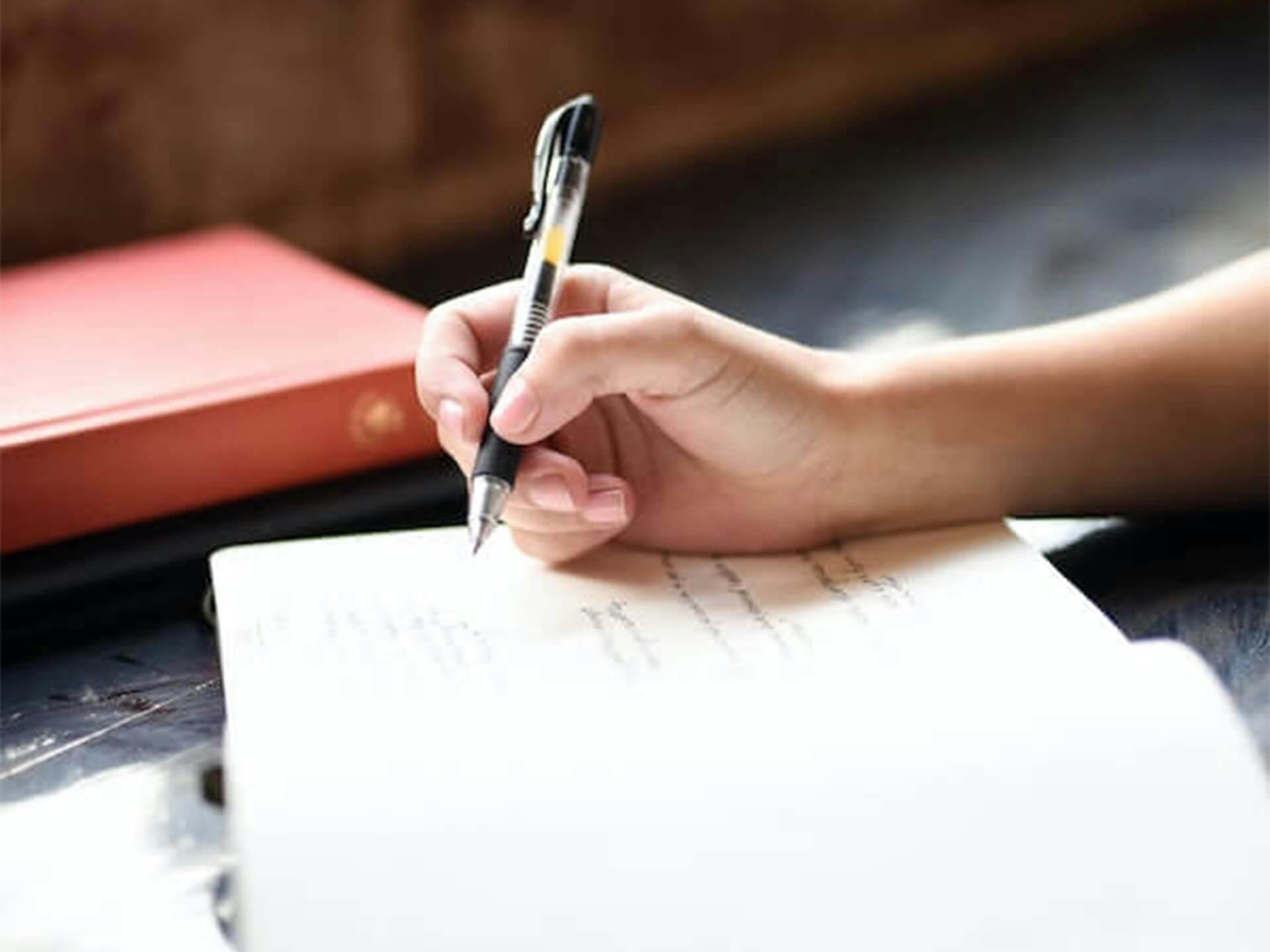 Lifestyle shot of someone writing in a notebook with a pen 