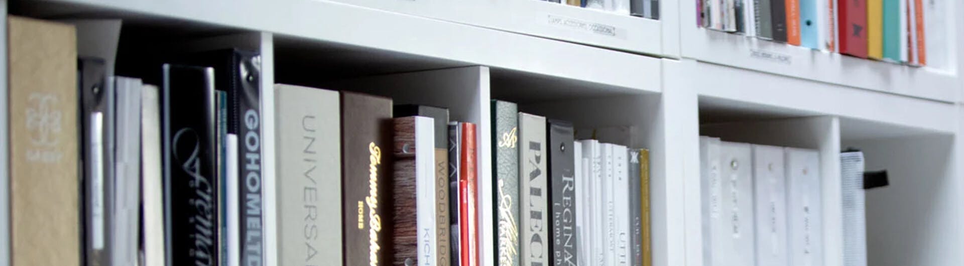 Close up of a large collection of a variety of books on a white shelf